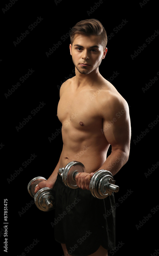 Muscle young man holding dumbbells on dark background Muscle young man holding dumbbells on dark background