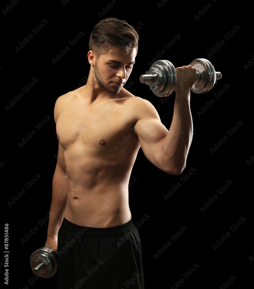 Muscle young man holding dumbbells on dark background Muscle young man holding dumbbells on dark background