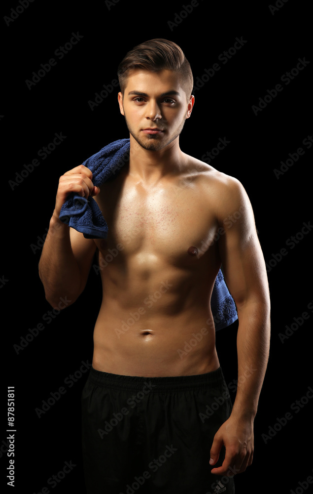 Muscle young man holding towel on dark background