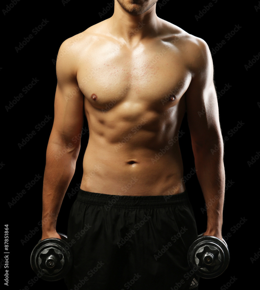 Muscle young man holding dumbbells on dark background