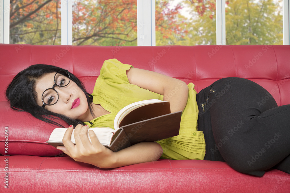 Young woman reading book on sofa