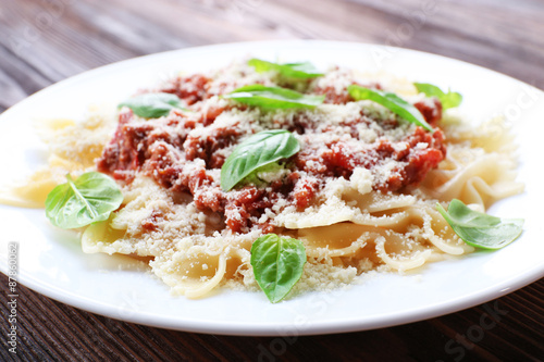 Pasta bolognese in white plate on wooden table, closeup