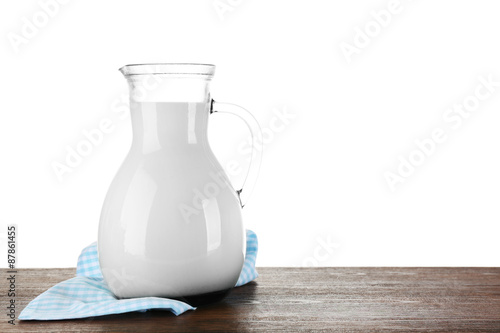 Pitcher of milk on wooden table, on white background