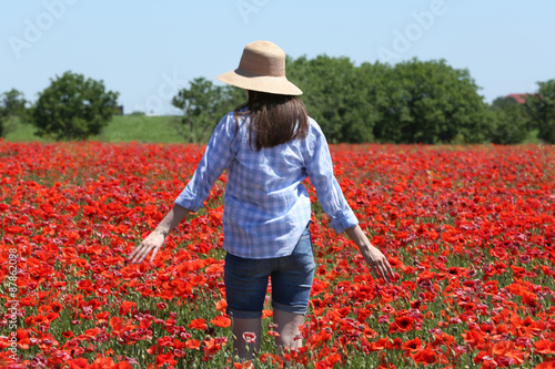 Woman walking on poppy field over blue sky background