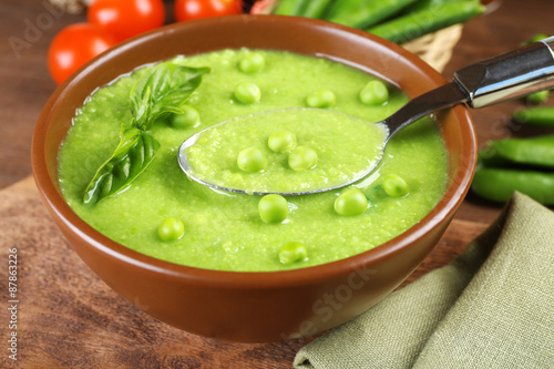 Tasty peas soup and cherry tomatoes on table close up