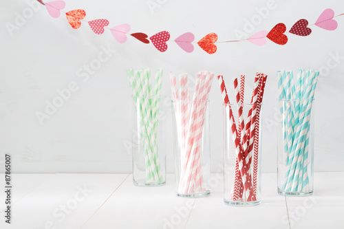 Obraz na plátně Colorful paper straws with a garland of hearts
