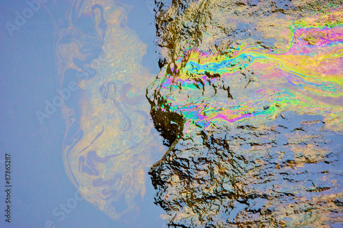 rainbow reflection of crude oil spill on the stone at the beach photo