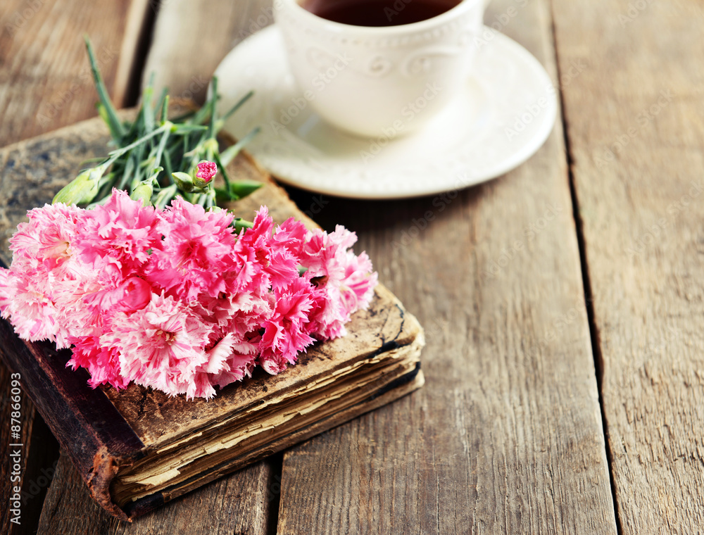 Old book with beautiful flowers and cup of tea on wooden table close up Old book with beautiful flowers and cup of tea on wooden table close up
