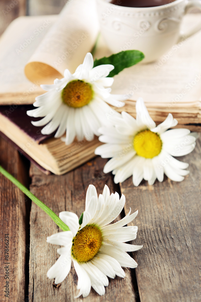 Old book with beautiful flowers and cup of tea on wooden table close up Old book with beautiful flowers and cup of tea on wooden table close up