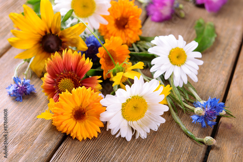 Bright wildflowers on wooden table  closeup