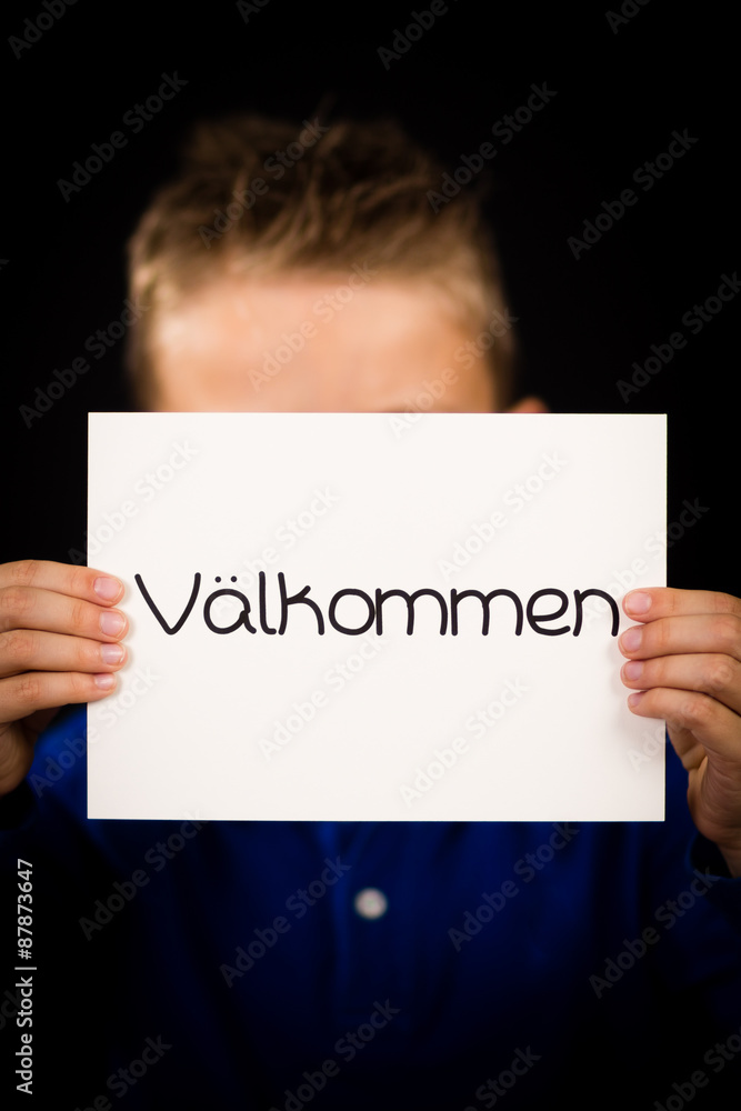 Child holding sign with Swedish word Valkommen - Welcome Child holding sign with Swedish word Valkommen - Welcome