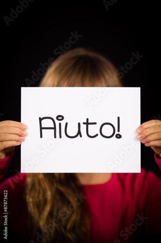 Child holding sign with Italian word Aiuto - Help