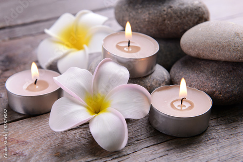 Beautiful spa composition with candles and flowers on wooden table close up