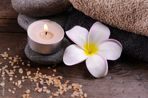 Beautiful spa composition and candle with flower on wooden table close up