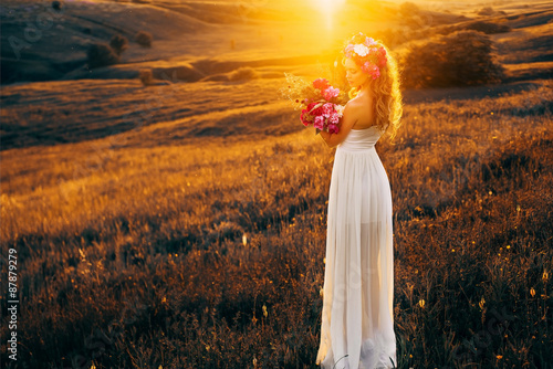 beautiful girl model in white dress with a bouquet of peonies in the sunset