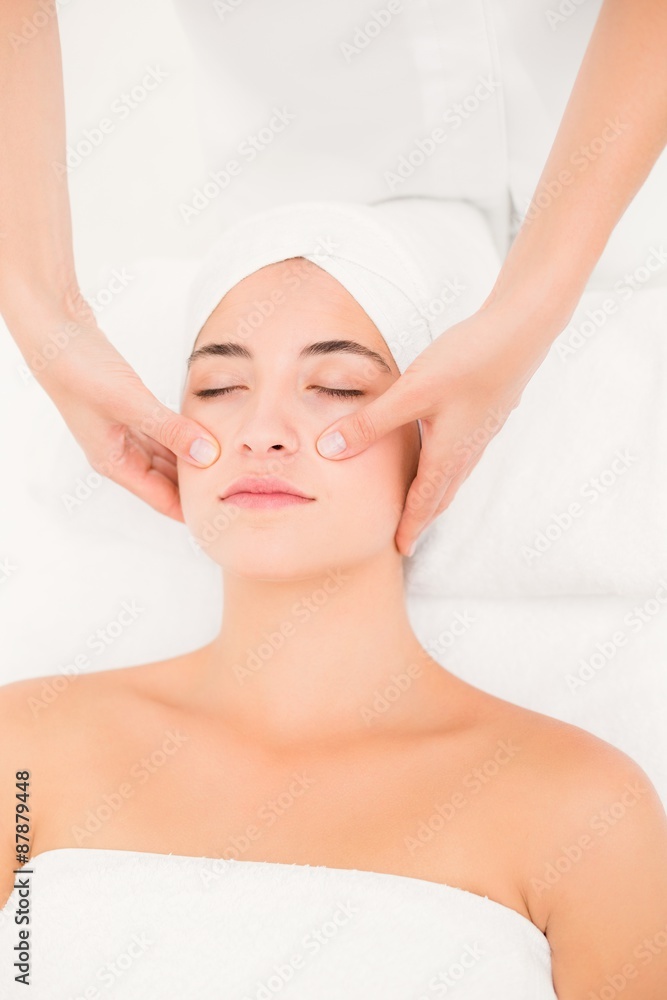 Attractive young woman receiving facial massage at spa center