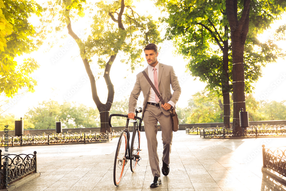 Confident businessman walking with bicycle