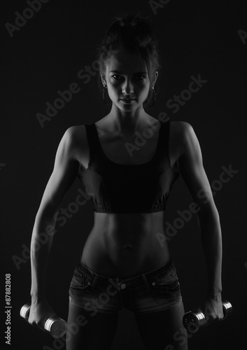 sporty girl doing exercise with dumbbells bw studio shot