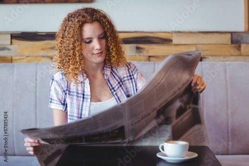 Pretty curly hair girl having cup of coffee and reading newspape photo