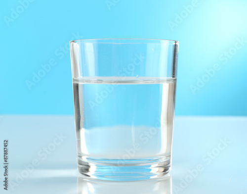 Glass of water on blue background