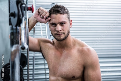 Portrait of muscular man leaning against gym equipment