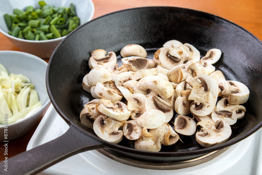 Sliced champignon mushrooms on cast iron skillet , ready to cook mushroom sauce Sliced champignon mushrooms on cast iron skillet , ready to cook mushroom sauce