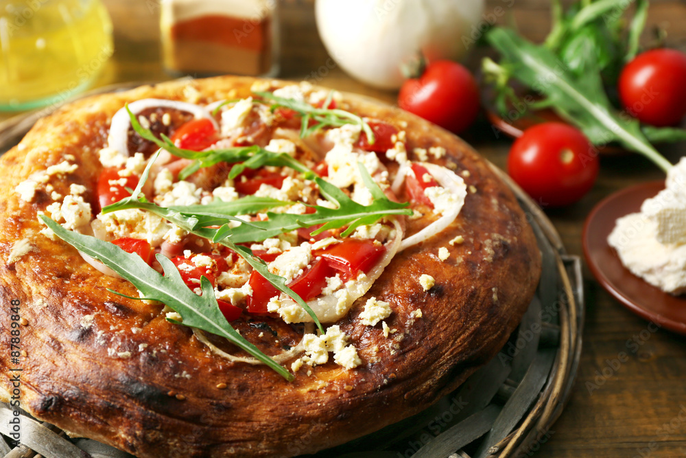 Greek homemade pizza with ham,onion, roasted tomato, creamy feta on wooden table background Greek homemade pizza with ham,onion, roasted tomato, creamy feta on wooden table background