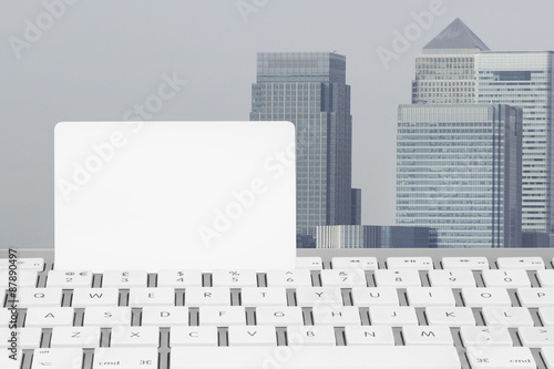 Blank white Credit card on a computer keyboard with Canary Wharf