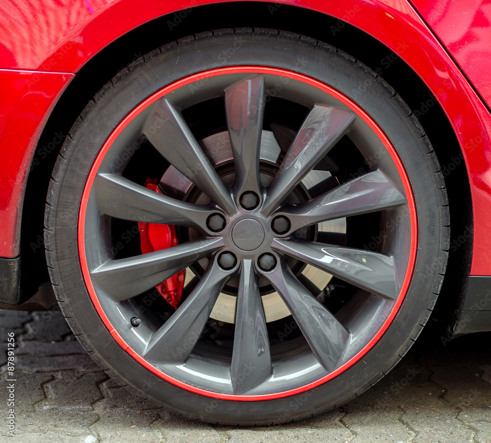 Red sports car wheel on the road.