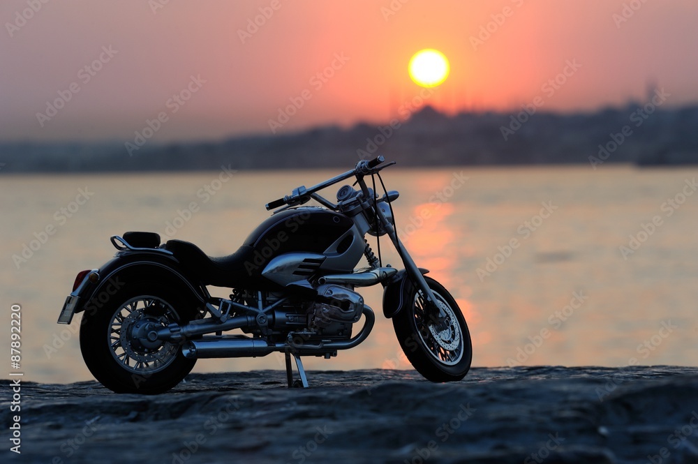 Naklejka premium Motorcycle on the rocks in sunset and golden hours