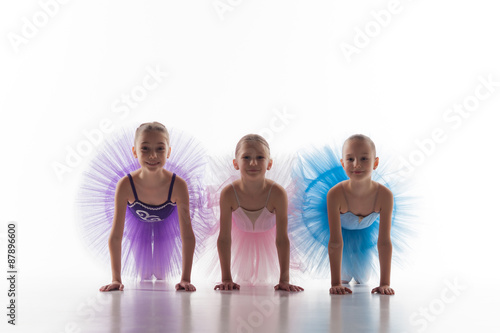 Three little ballet girls sitting in tutu and posing together
