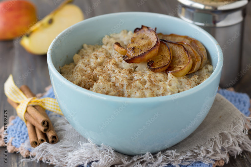 Oatmeal with baked apples and cinnamon in blue ceramic bowl on wooden table Oatmeal with baked apples and cinnamon in blue ceramic bowl on wooden table
