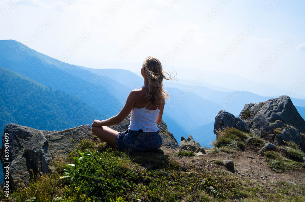 Naklejka premium Young blond woman meditating in the beautiful mountain landscape