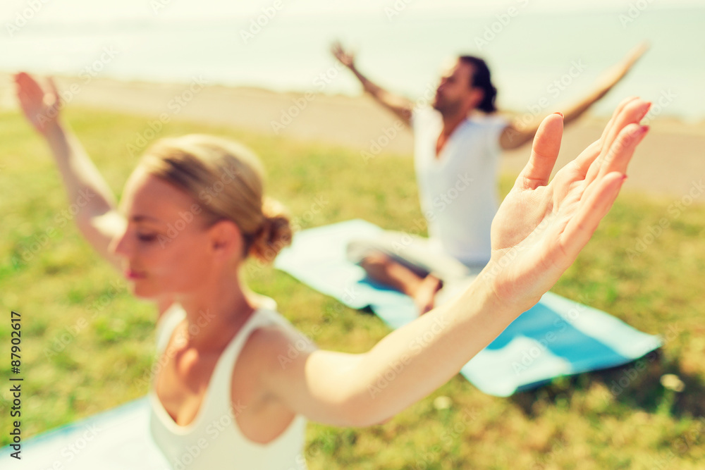 Fototapeta premium close up of couple making yoga exercises outdoors