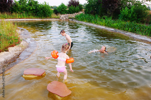 Spielende Kinder beim Baden und Planschen in einem Naturteich.