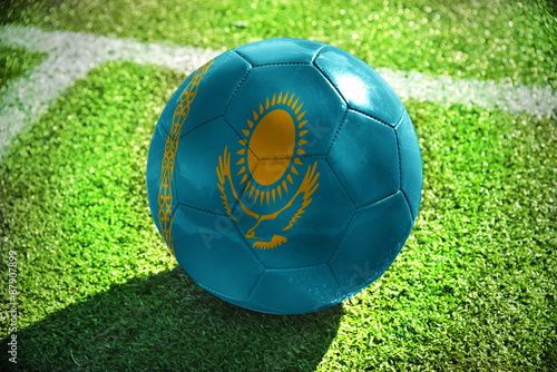 football ball with the national flag of kazakhstan lies on the green field near the white line