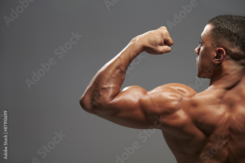 Male bodybuilder flexing bicep  back view with copy space