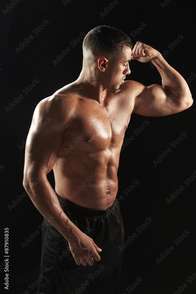 Male bodybuilder looking at his flexing muscles