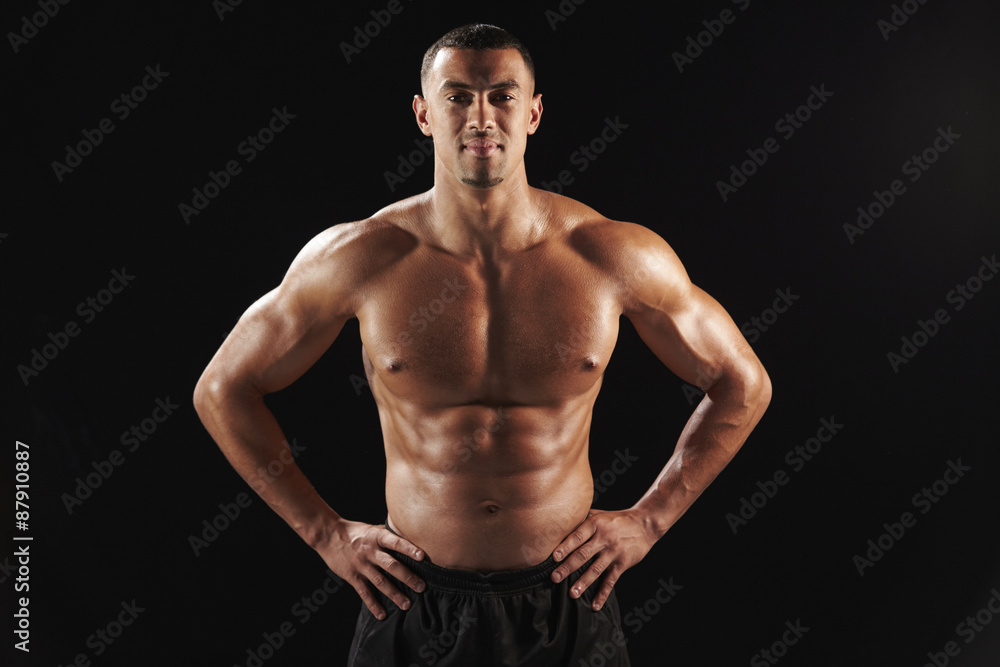 Fototapeta premium Smiling bare chested male body builder with hands on hips
