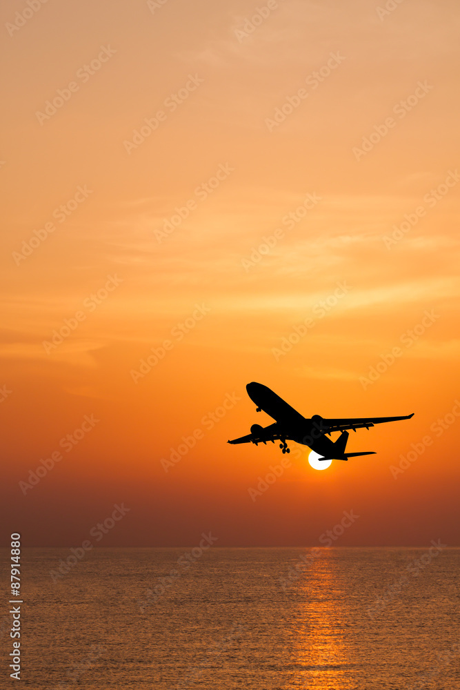 Silhouetted commercial airplane flying above the sea at sunset Silhouetted commercial airplane flying above the sea at sunset