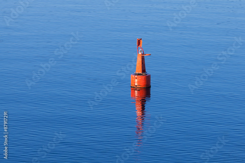 Red modern navigation buoy on still water