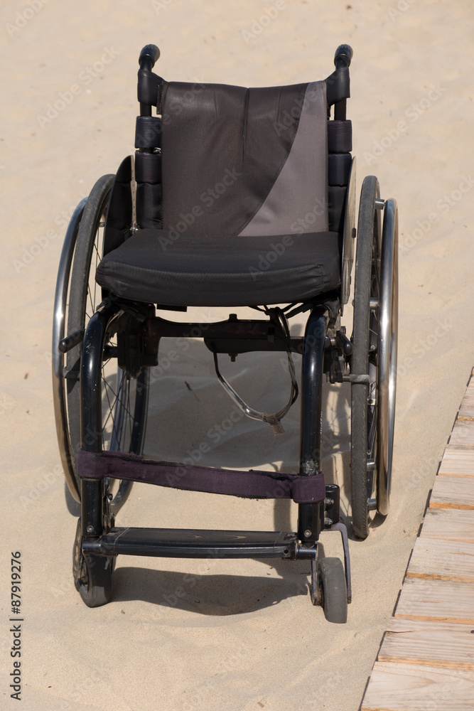 Empty wheelchair sits vacant on a beach of sand Empty wheelchair sits vacant on a beach of sand