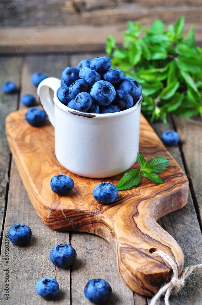 Organic fresh blueberries with peppermint on a wooden background