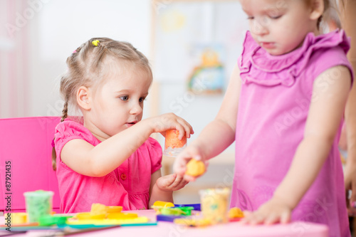 Little girls playing with plasticine in school