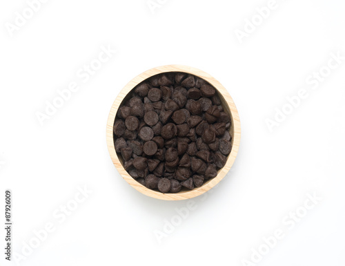 Chocolate chips in wooden spoon and bowl on white background