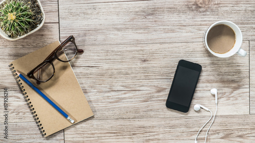 Smartphone, earphones, notebook and coffee on wooden background
