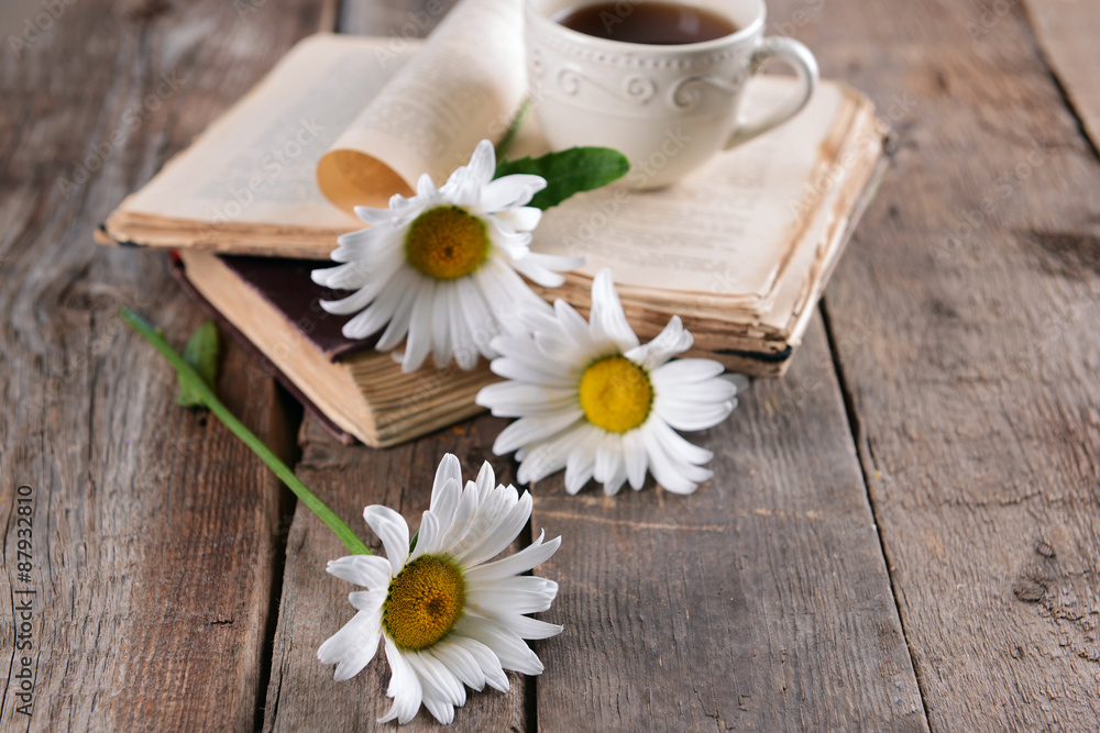 Old book with beautiful flowers and cup of tea on wooden table close up Old book with beautiful flowers and cup of tea on wooden table close up