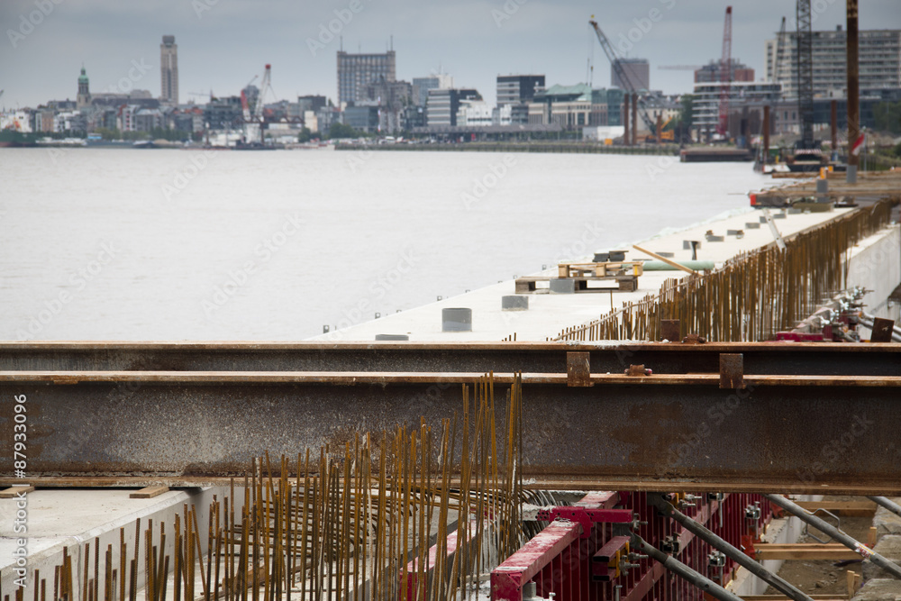 Construction works at the docks of the Schelde river with the Antwerp skyline in the background

