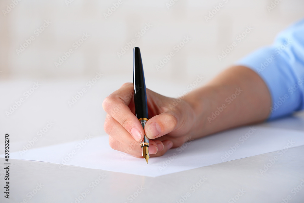 Female hand with pen writing on paper at workplace Female hand with pen writing on paper at workplace