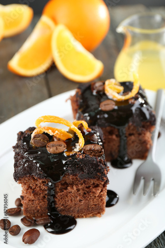 Portion of Cake with Chocolate Glaze and orange on plate, on wooden background